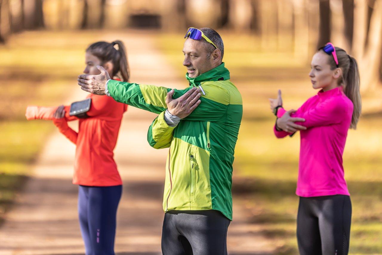 Adulte s’échauffant avec un coach lors d’un entraînement de musculation dans le parc, illustration de l’important adult warm-up coaching.