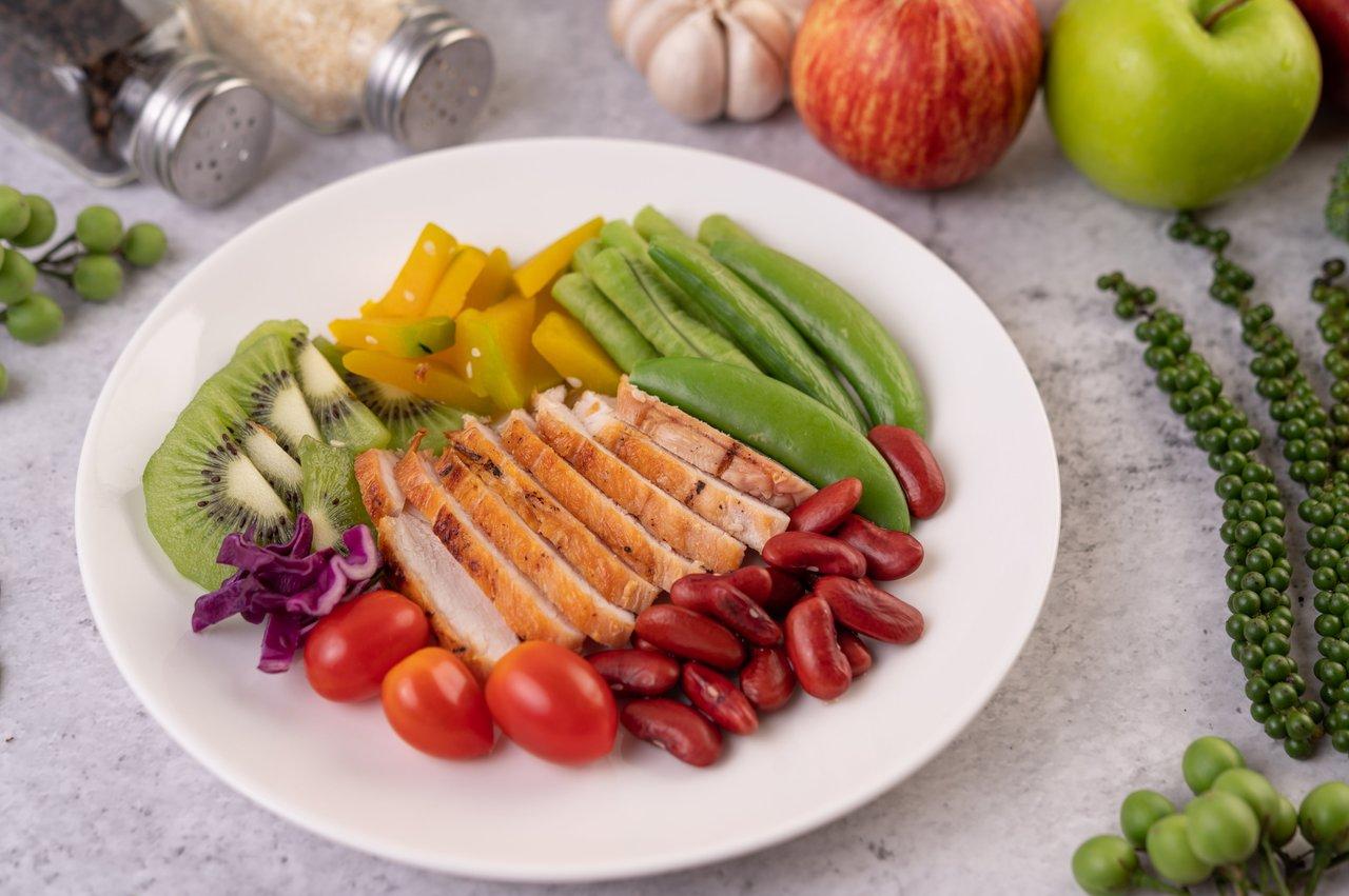 Assiette équilibrée avec poulet, légumes et kiwi, idéale pour un healthy balanced dinner plate favorisant le sommeil réparateur.