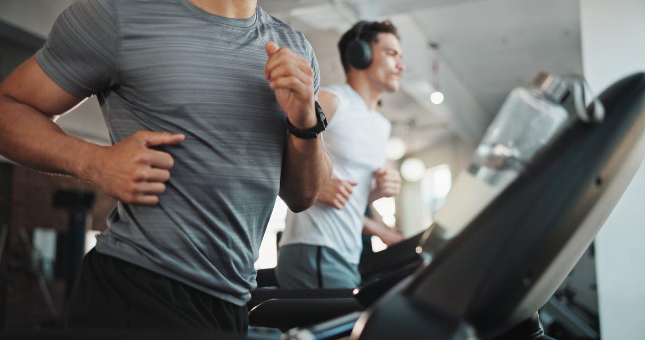 Comparaison entre HIIT et cardio traditionnel : homme courant sur tapis pour optimiser la dépense calorique.