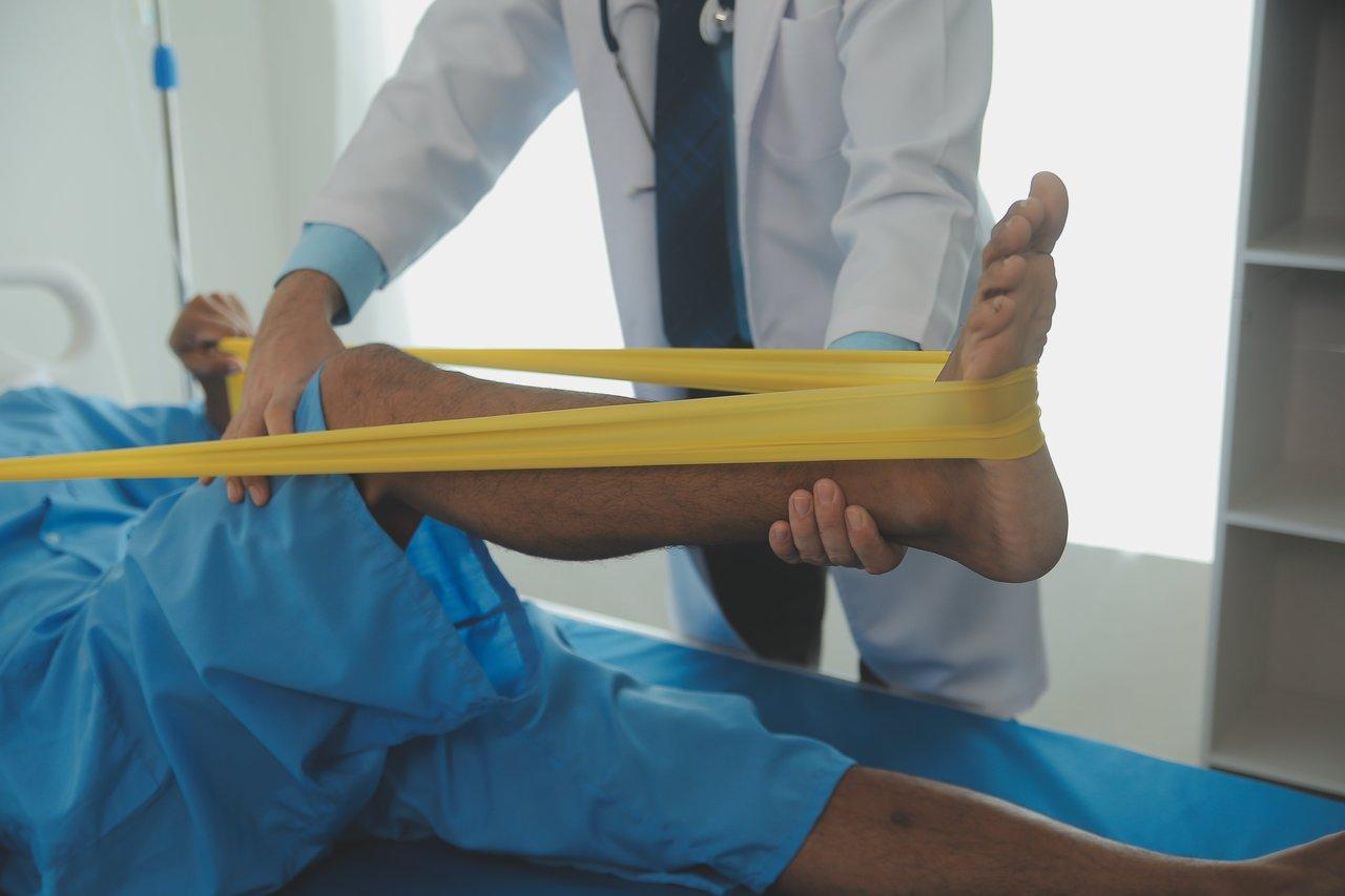 Exercice de tirage avec bande élastique pour la réhabilitation musculaire après une blessure légère.