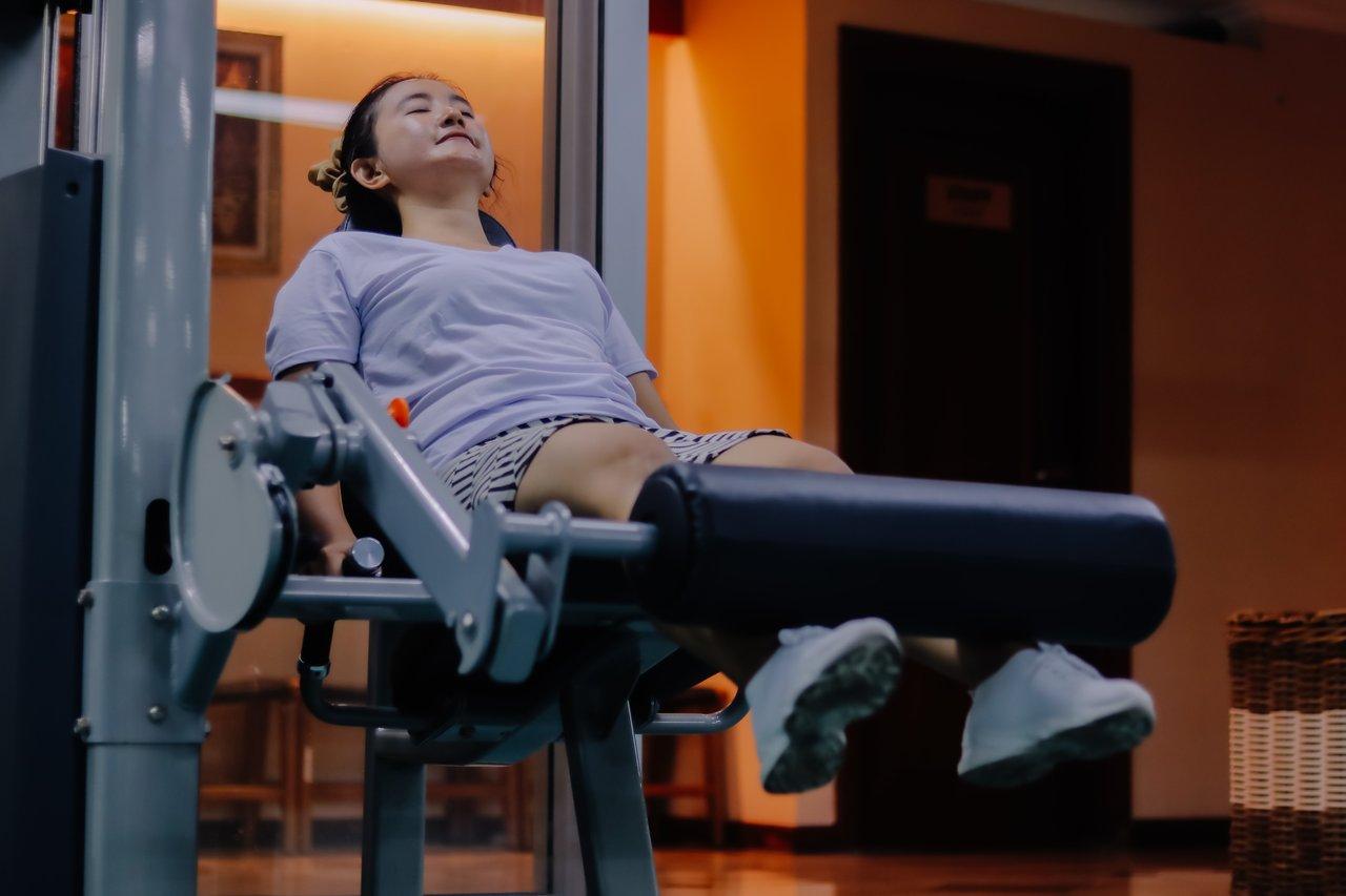 Femme réalisant un exercice de woman floor leg curl pour sculpter ses jambes avant l’été.