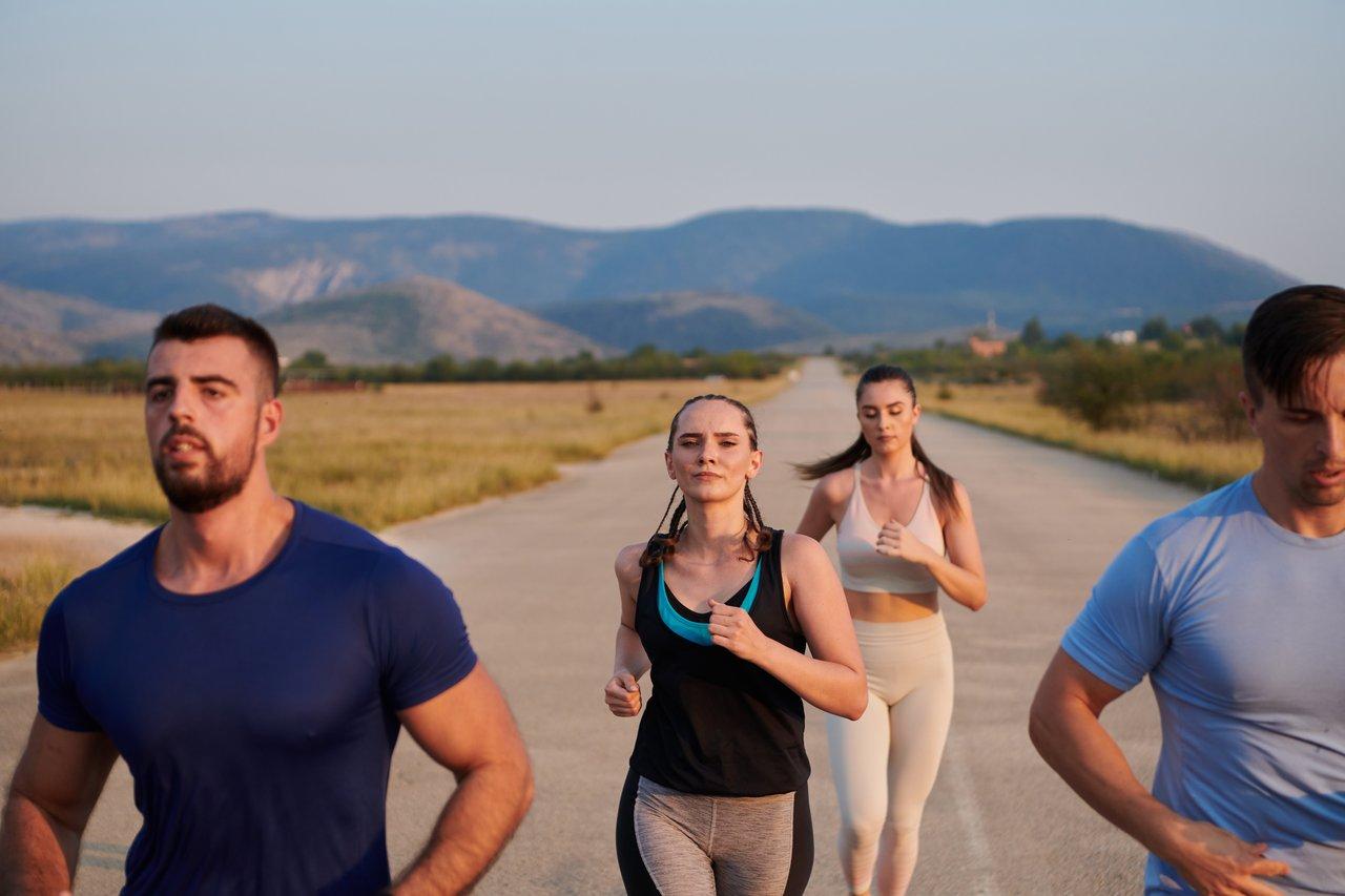 Groupe de coureurs en plein air souriants, illustrant la motivation et la convivialité lors d'une séance de running en nature.