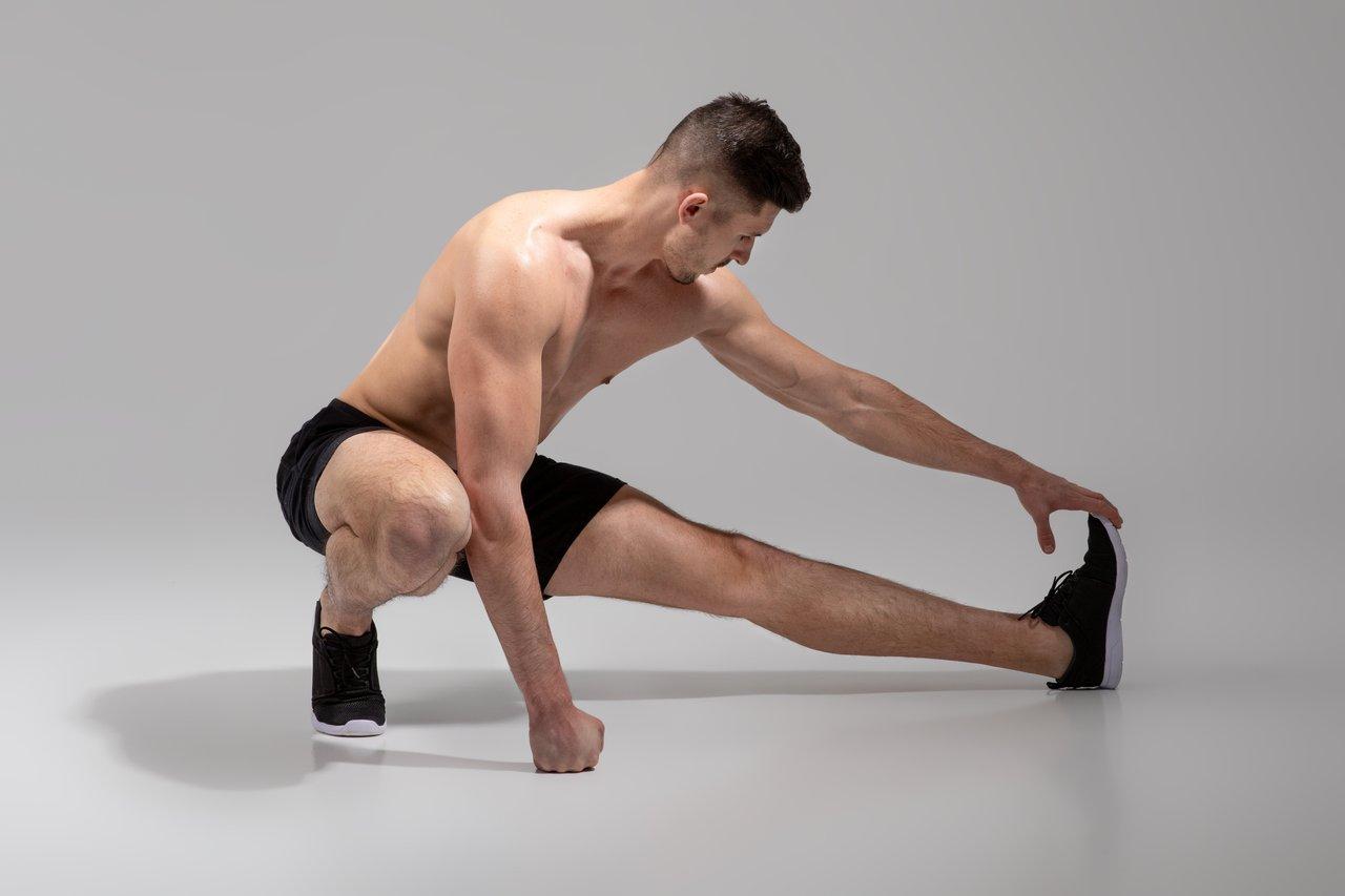 Homme sportif en entraînement, pratique un leg workout stretching pour des jambes légères et prêtes.