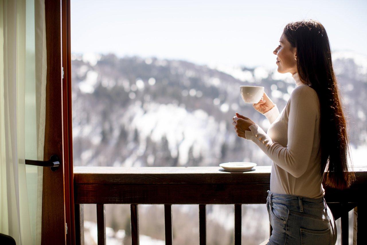 Personne buvant de l'eau près d'une fenêtre en hiver, ambiance festive et calme pour gérer le stress des fêtes.