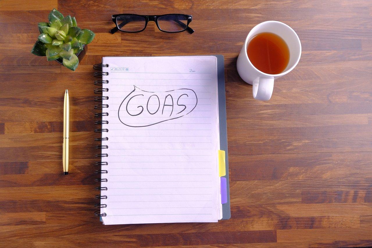 Personne écrivant ses objectifs dans un espace de travail lumineux et motivant, idéal pour booster sa motivation.