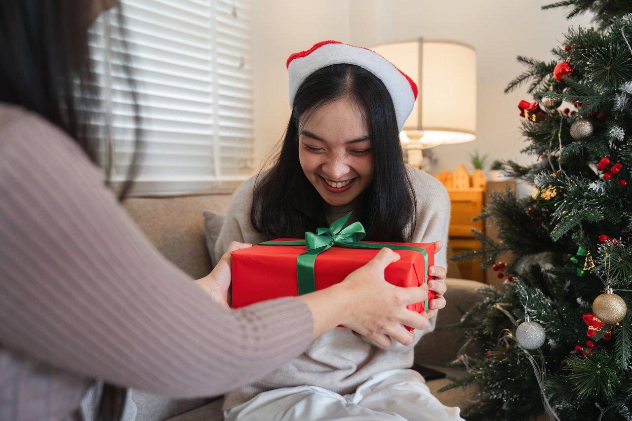 Personne souriante lors d’un échange de cadeaux convivial, symbole de joie et de partage en période festive.