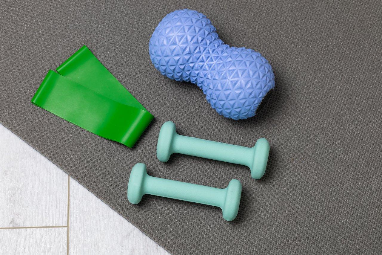 Tapis de fitness roulé et haltères réglables pour débuter une activité sportive à petit budget.